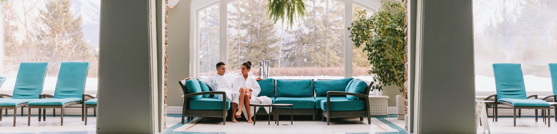 a couple sitting on a couch near the indoor pool