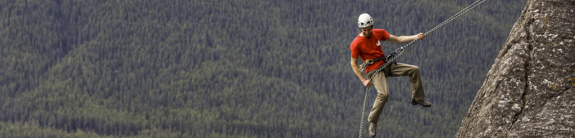 man rock climbing with a view of the hotel in the distance