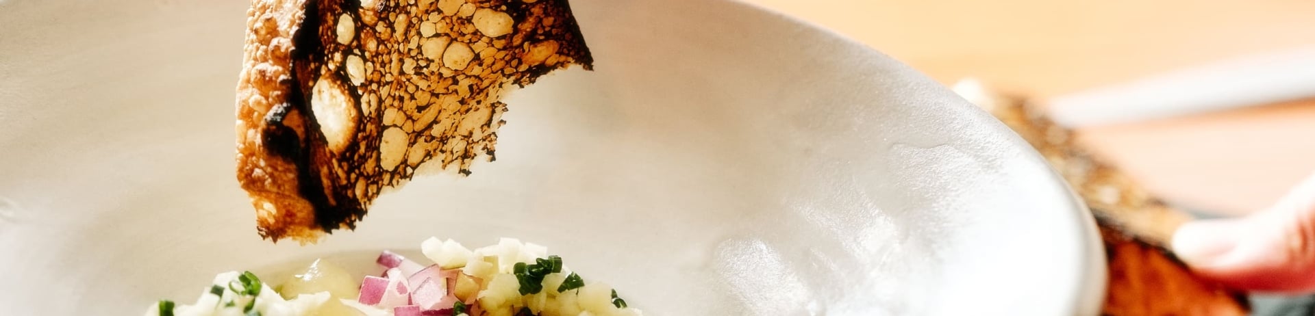 hand dipping bread into sauce