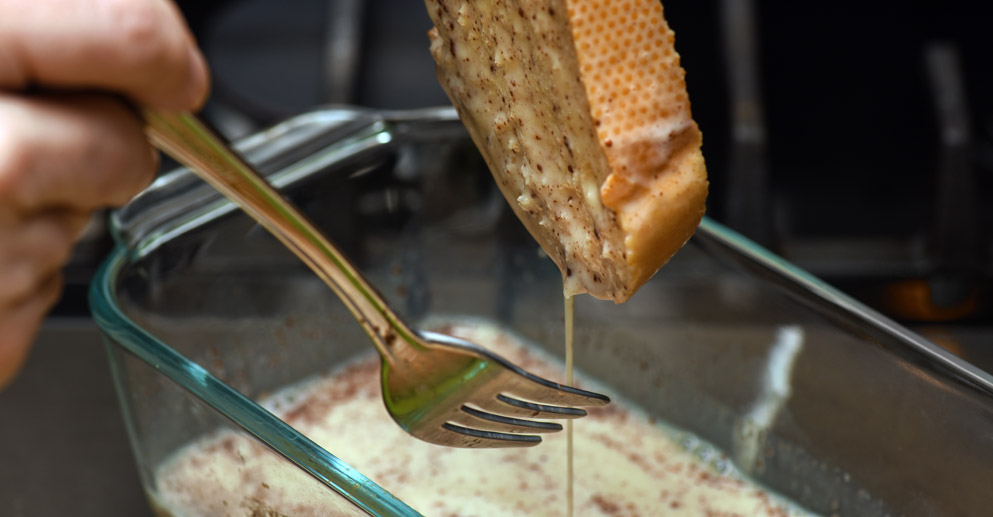 Baguette slice soaked in egg, vanilla, cinnamon and milk mixture while preparing French Toast