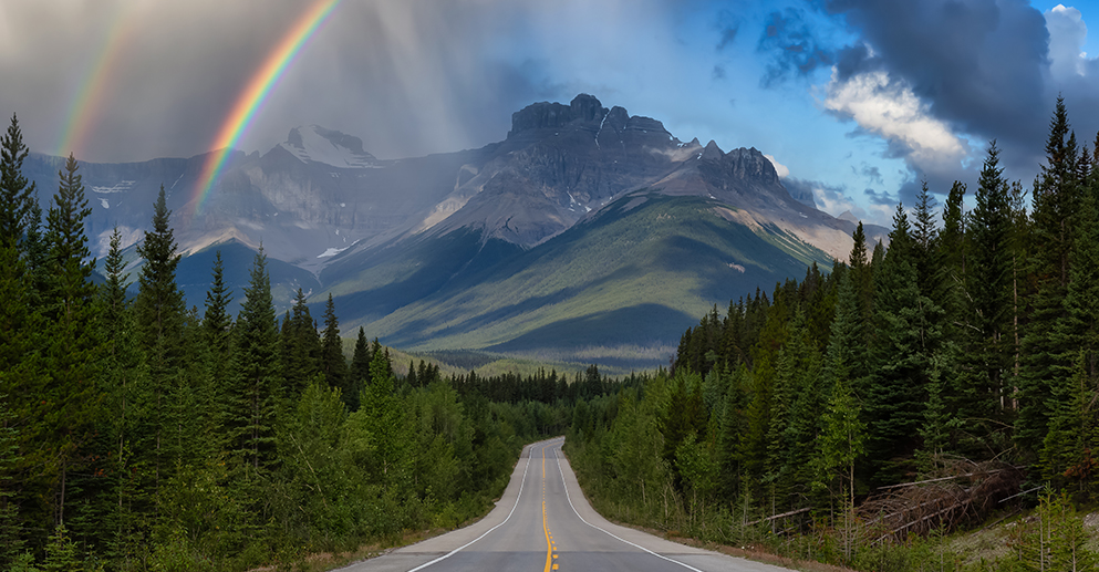 road with a view of the mountains and a rainbow