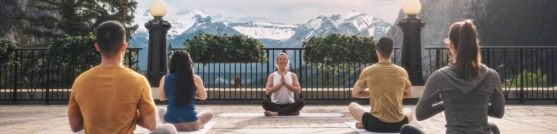 outdoor yoga class in a seated position with their hands at their hearts