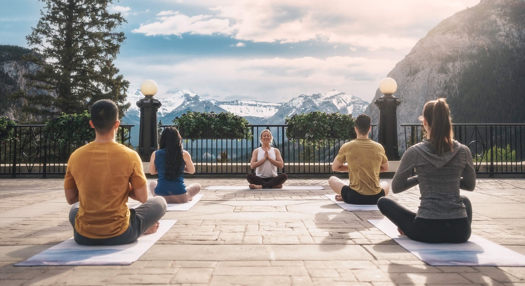 outdoor yoga class in a seated position with their hands at their hearts