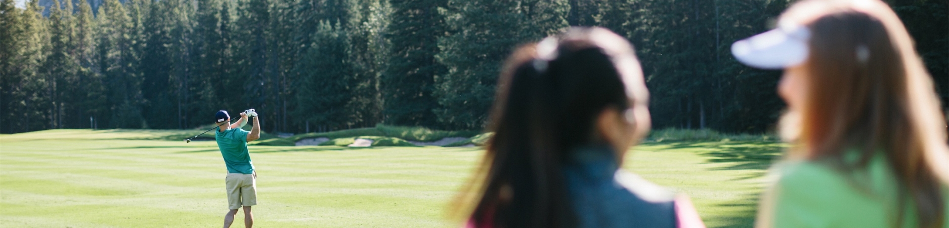 two women chatting while a man golfs