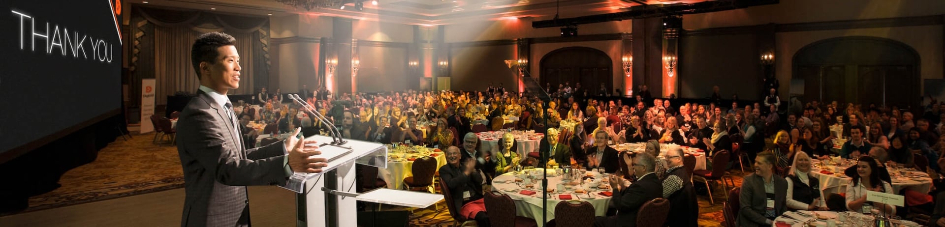 man giving a speech to a room full of guests