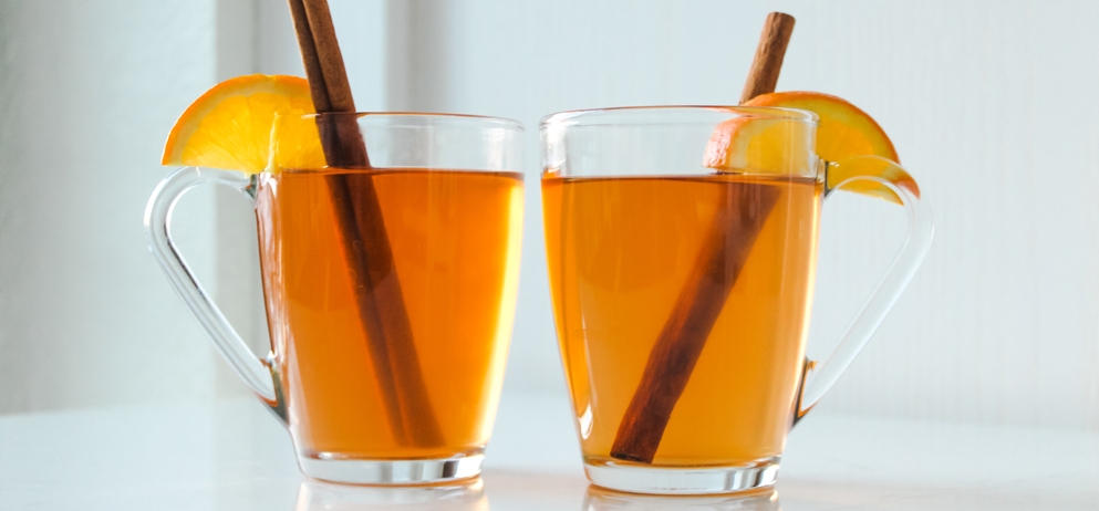 two cocktails with orange and cinnamon garnish