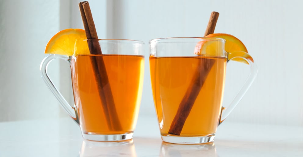 two cocktails with orange and cinnamon garnish