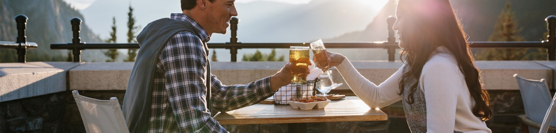 couple clinking glasses while eating dinner on a patio