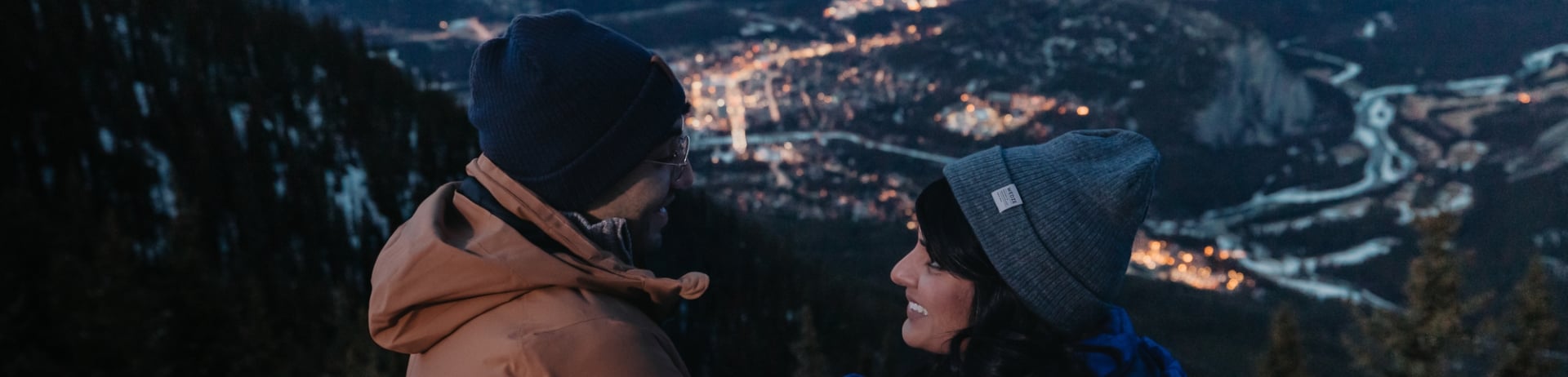 Couple looking over the town of Banff during Nightrise at the Banff Gondola