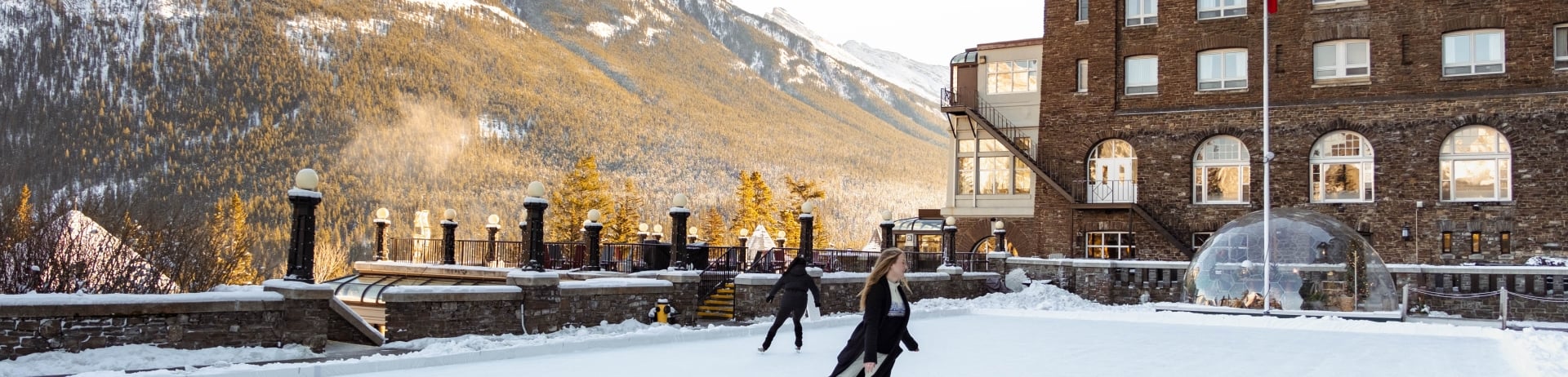 Two women ice skating on the terrace at Fairmont Banff Springs
