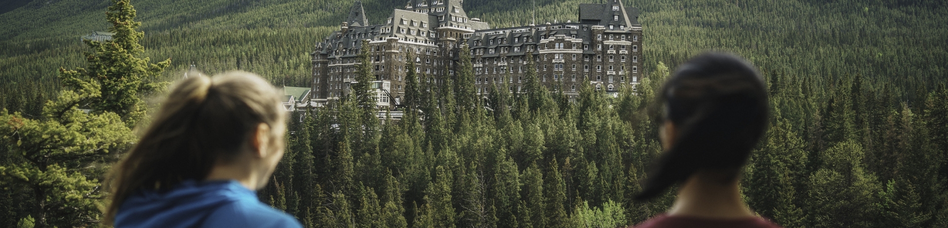 two women looking at a river and the Fairmont Banff Springs in the mountains