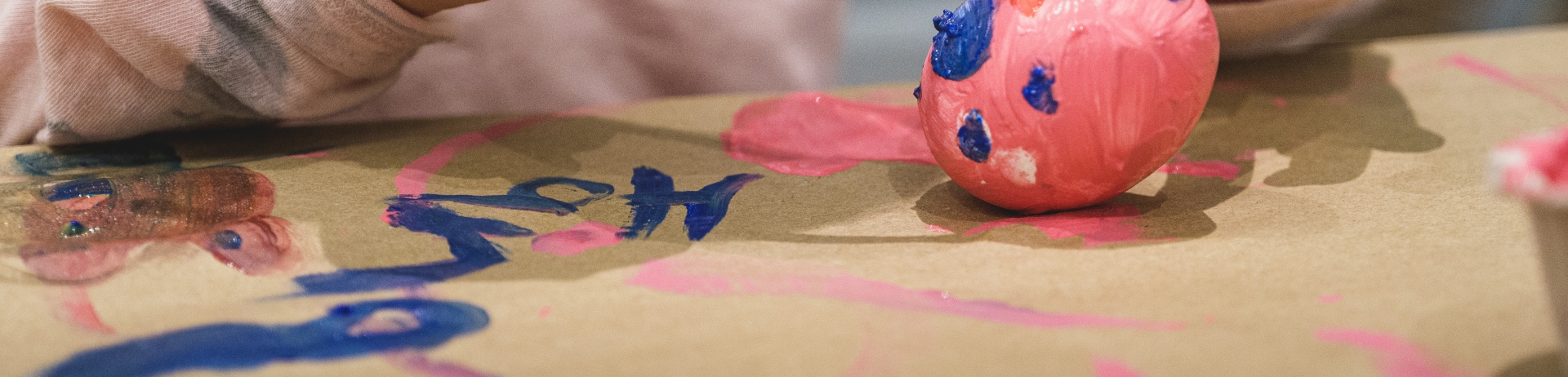 Child holding easter egg and painting it.