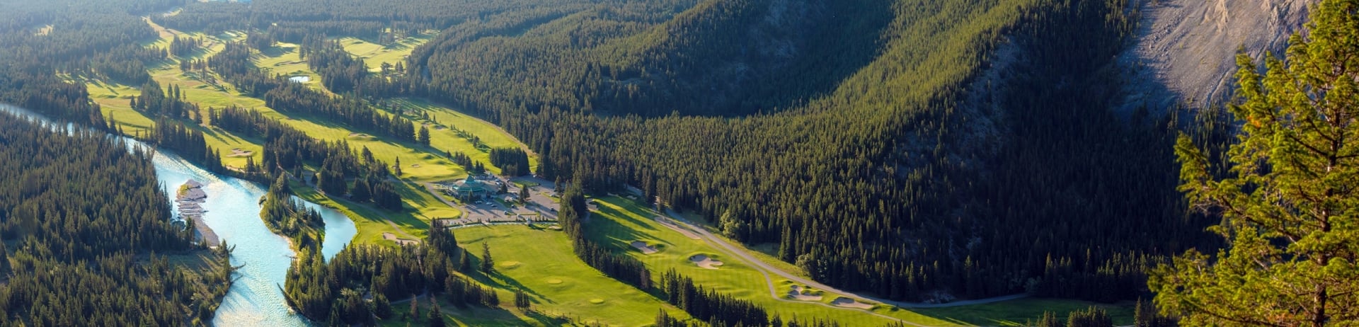 Aeriel shot of Banff Springs Golf Course with holes on the left and mountains on the right.