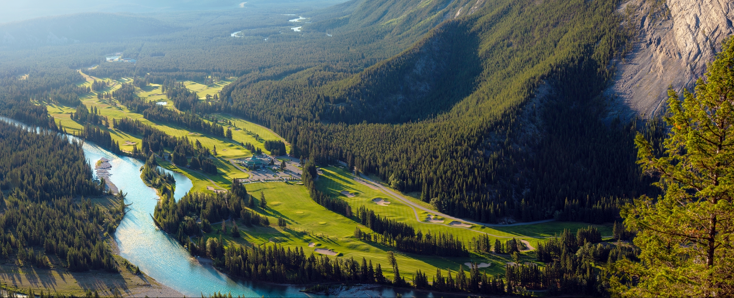 Aeriel shot of Banff Springs Golf Course with holes on the left and mountains on the right.