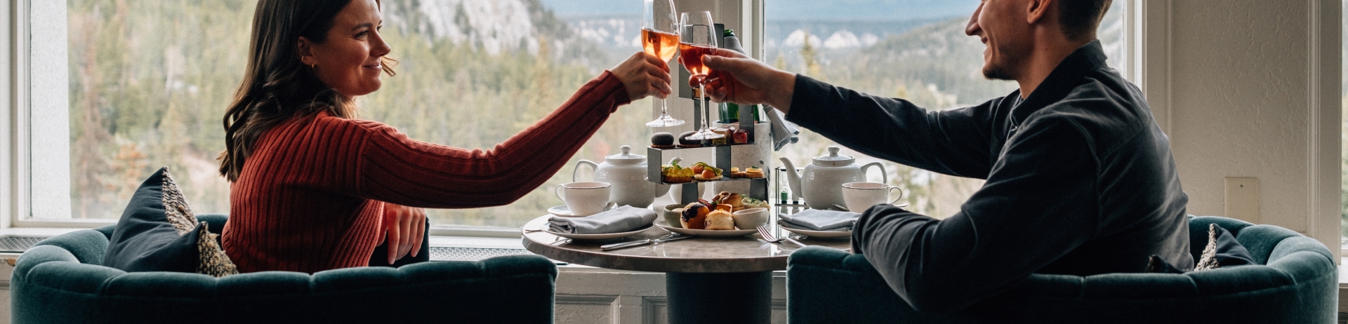 two people sitting in a restaurant with mountains in the background beyond the window.