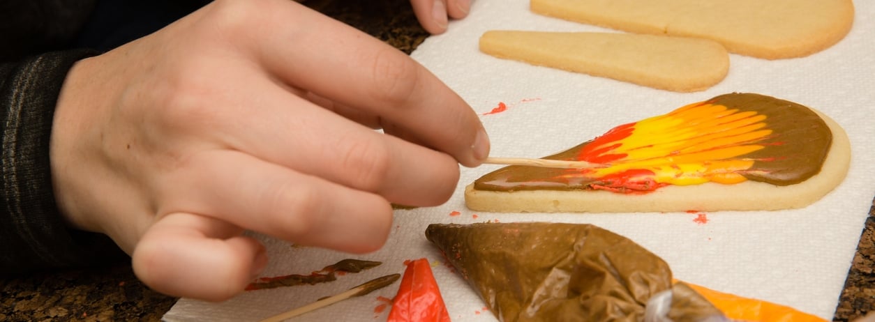 Child decorating Thanksgiving themed cookie.
