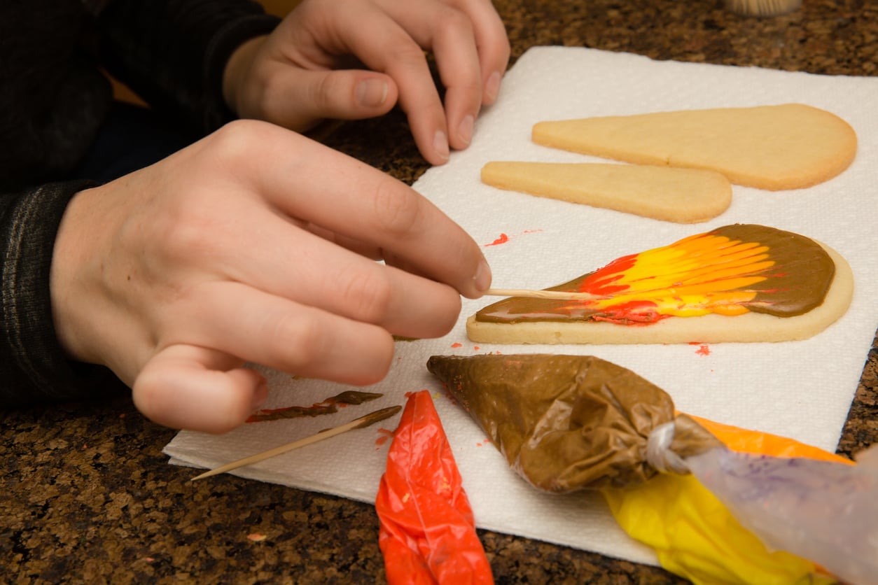 Child decorating Thanksgiving themed cookie.